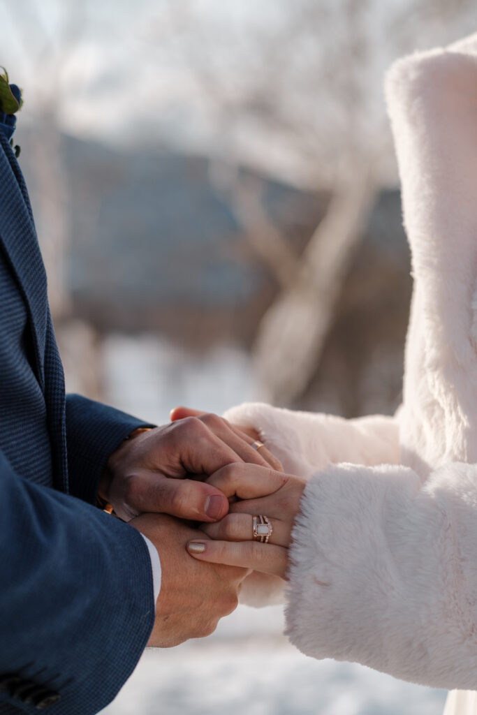Couple holding hands in the snow during winter elopement in the White Mountains