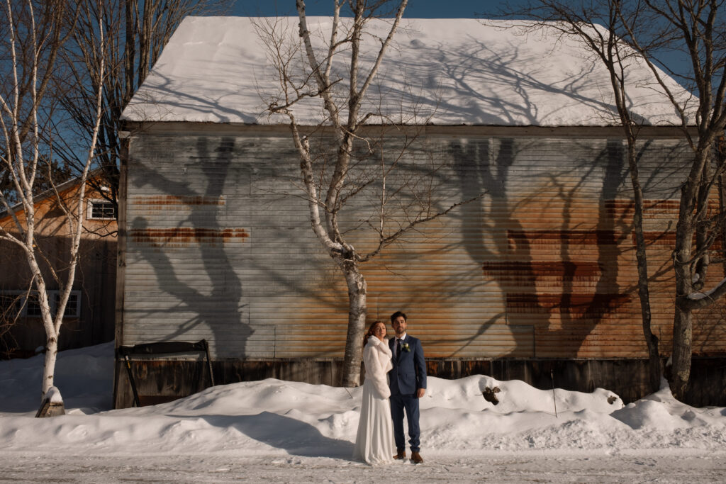 Bride and groom in front of a barn in the snow in Jackson, NH