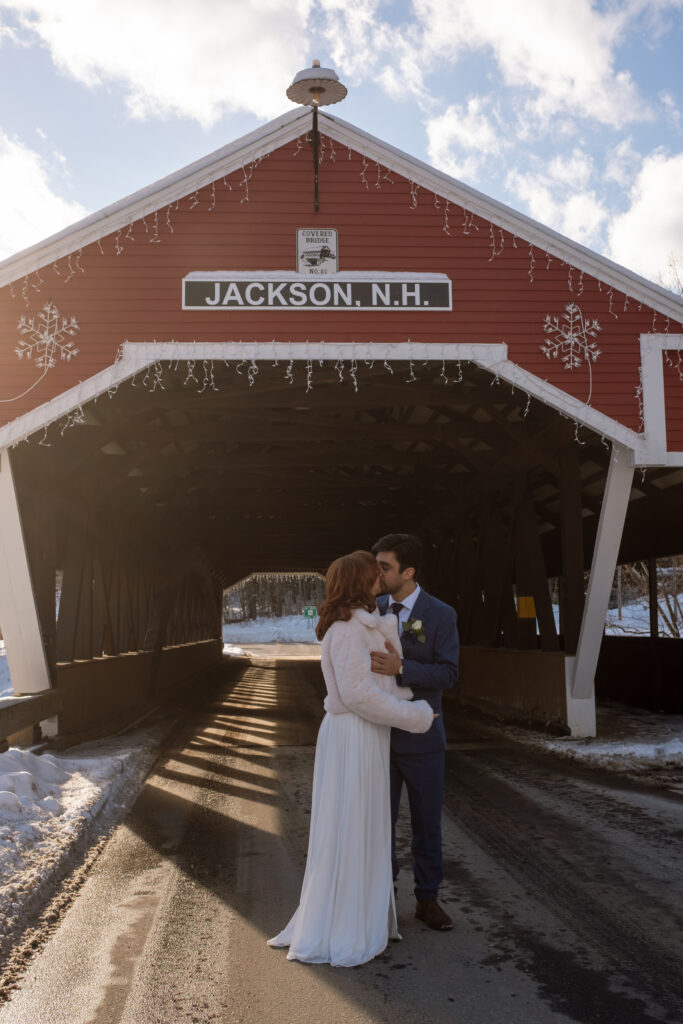 Bride and groom on covered bridge during winter elopement in New Hampshire