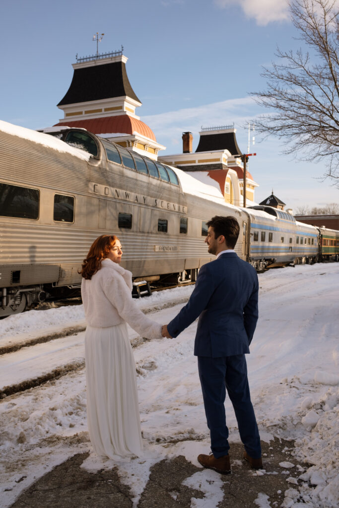 Bride and groom in the snow outside Conway Scenic Railroad train station in New Hampshire